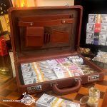 نمای داخلی کیف دلار جهانگردی انارکالا با چیدمان حرفه‌ای بسته‌های اسکناس سینمایی و سکه‌های دکوری